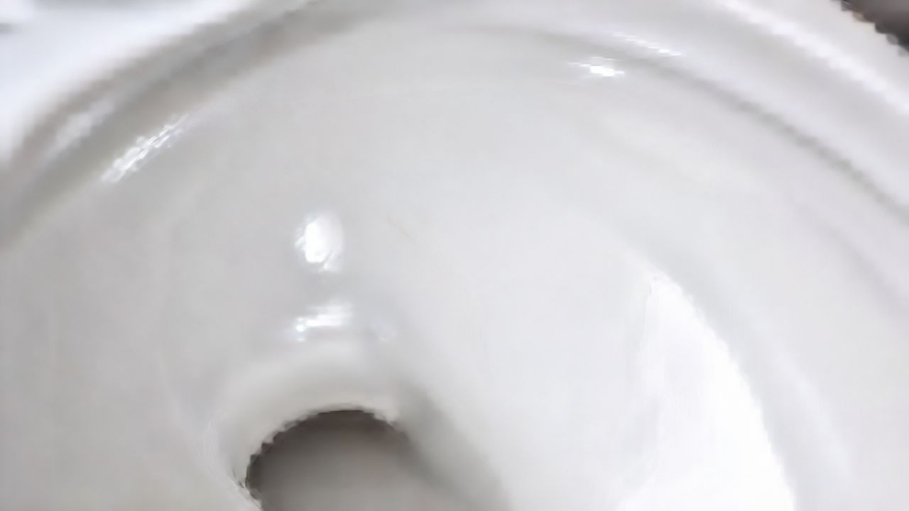 Nærbillede af den indvendige hvide overflade og afløbet i et rent, moderne keramisk toilet
